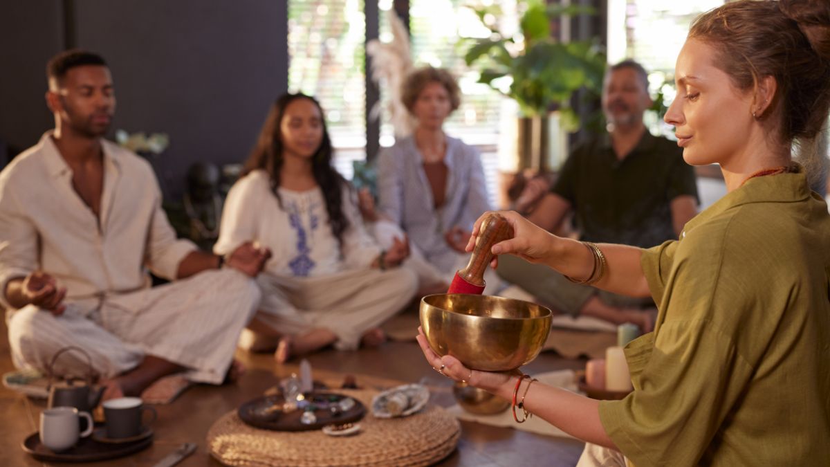 Egy nő aranytálat használ, miközben gyógyító csoport meditál egy szobában.