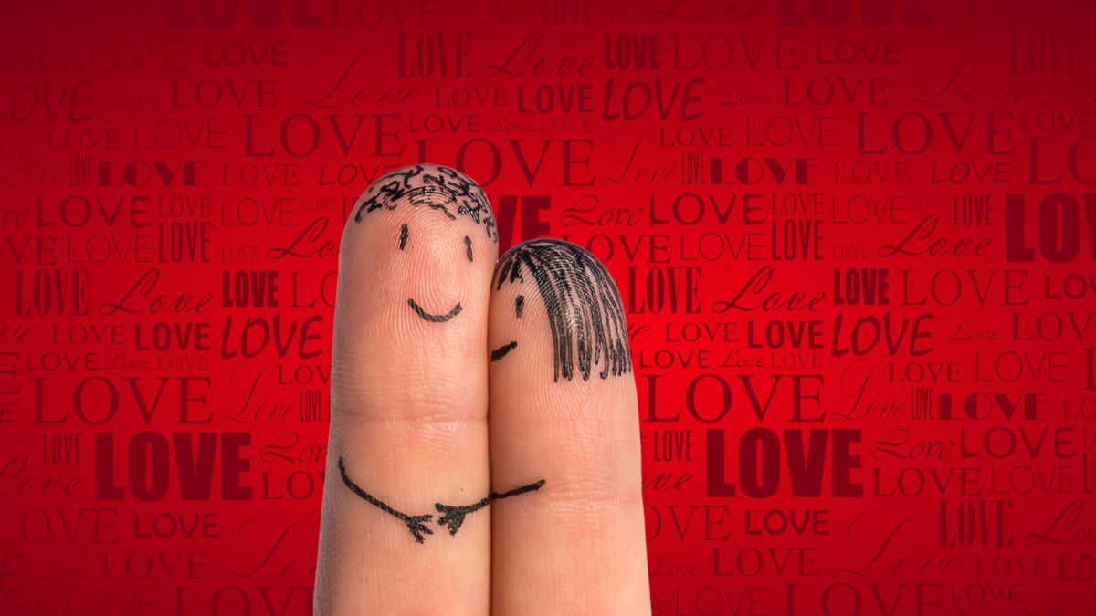 Két ujjra rajzolt boldog arcok, háttérben a 'love' szóval.